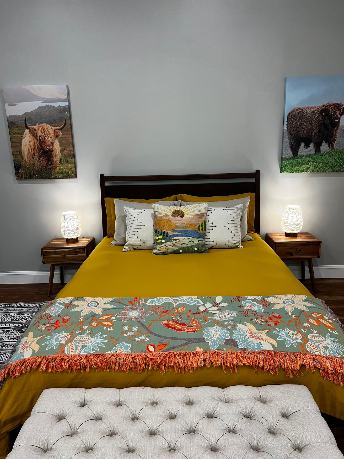 Queen bed with mustard bedding and Highland cattle artwork